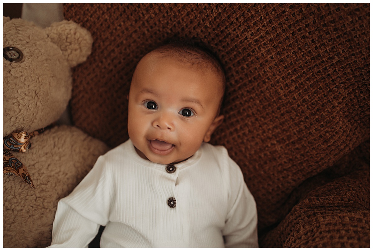 infant smiles sitting in chair for Denver newborn photographer