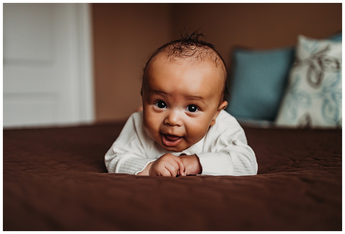 infant rests on his arms on bed for  Denver newborn photographer