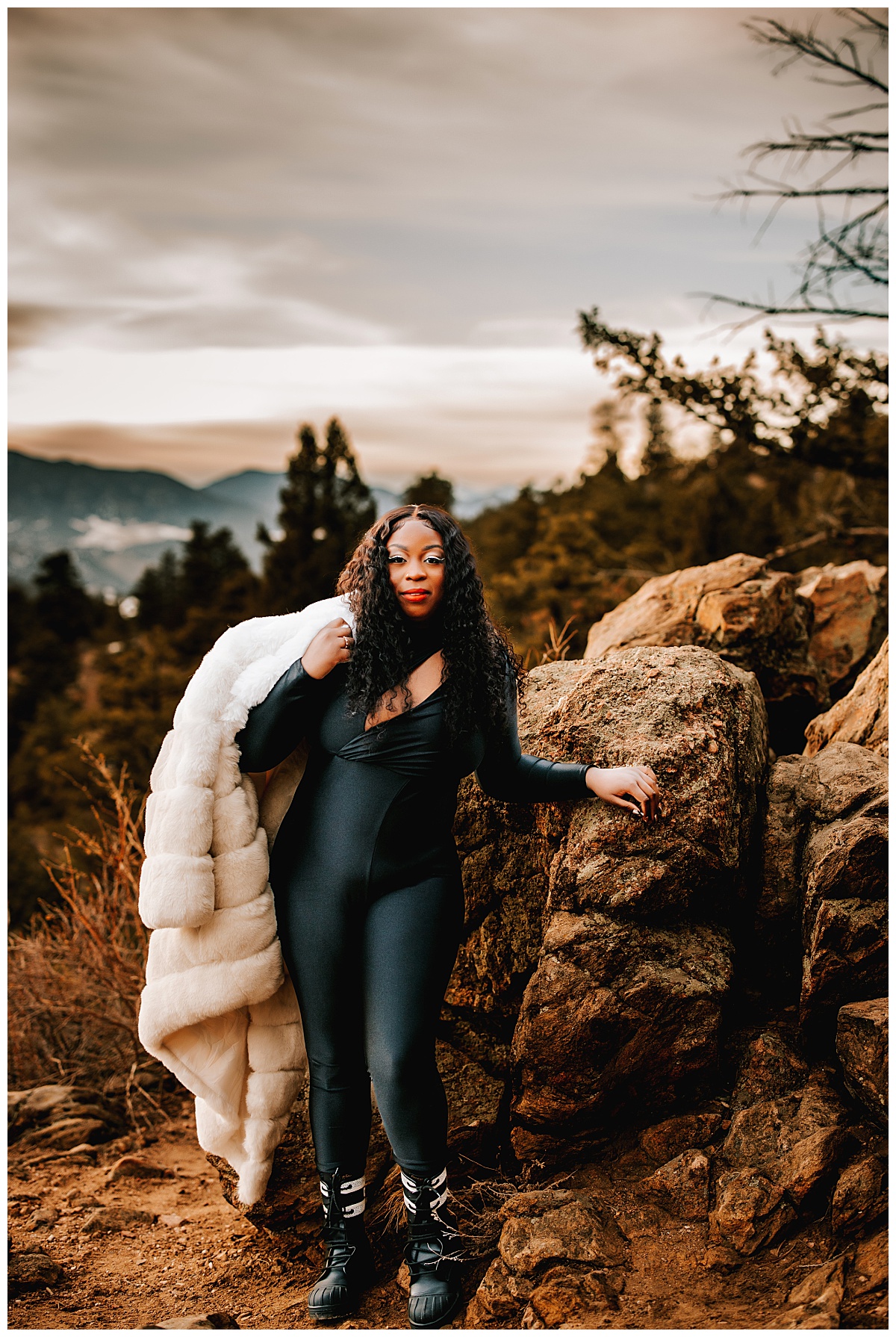 Samanda leans on a rock with fur coat over her shoulder