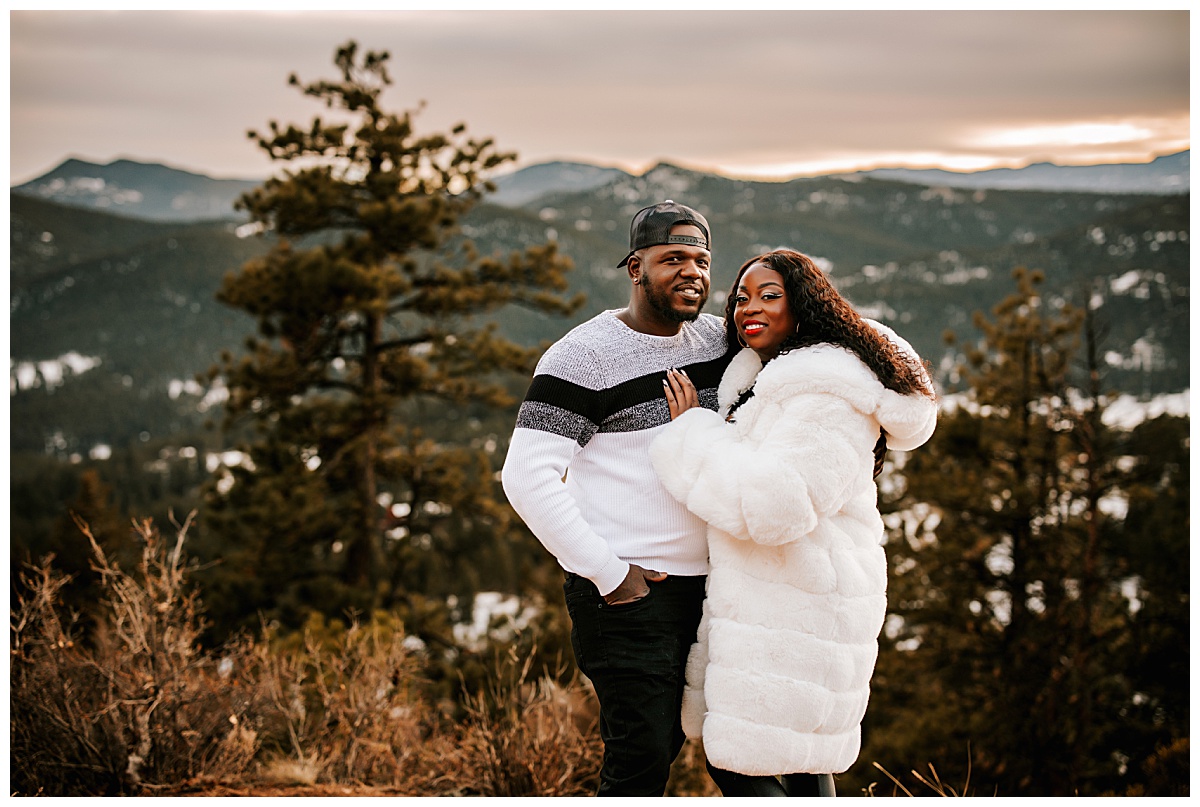 Samanda puts her hand on her boyfriend's chest in front of snowcapped mountains