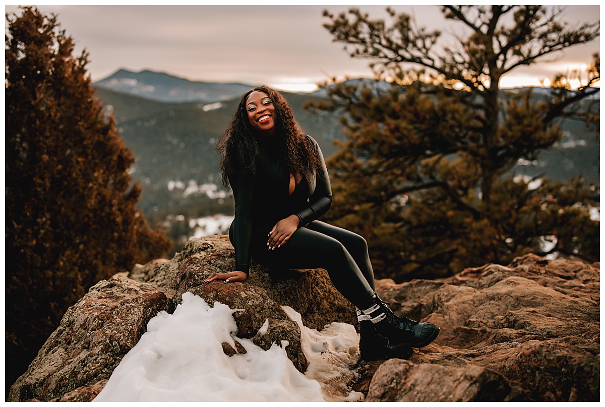woman laughs sitting on rock in black outfit