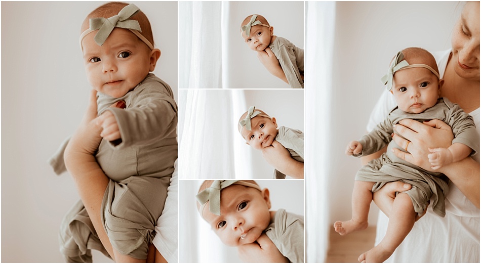 mom holds newborn baby girl in olive green outfit near window