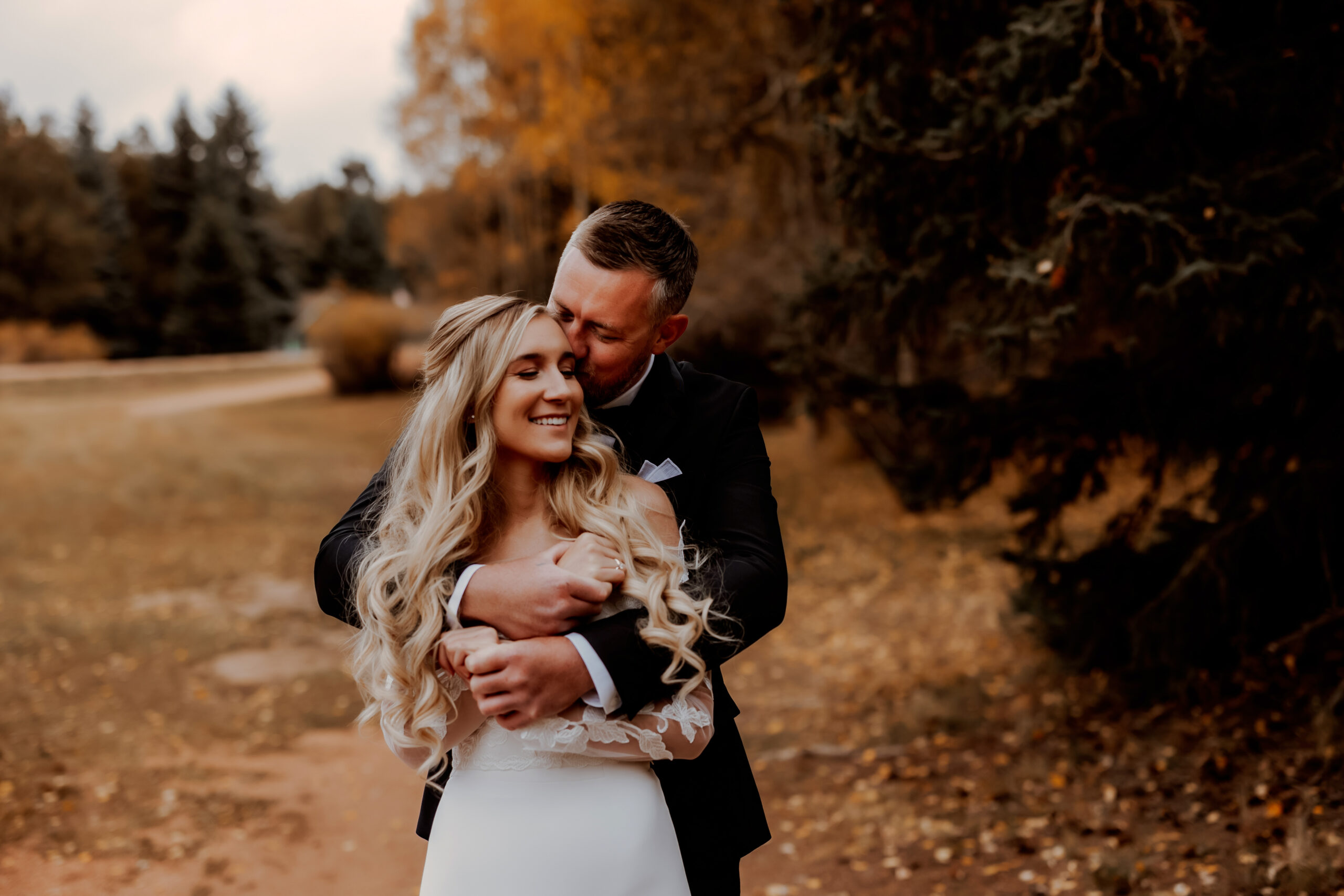 Colorado couple cuddle for fall wedding ceremony with yellow aspen leaves in the mountains