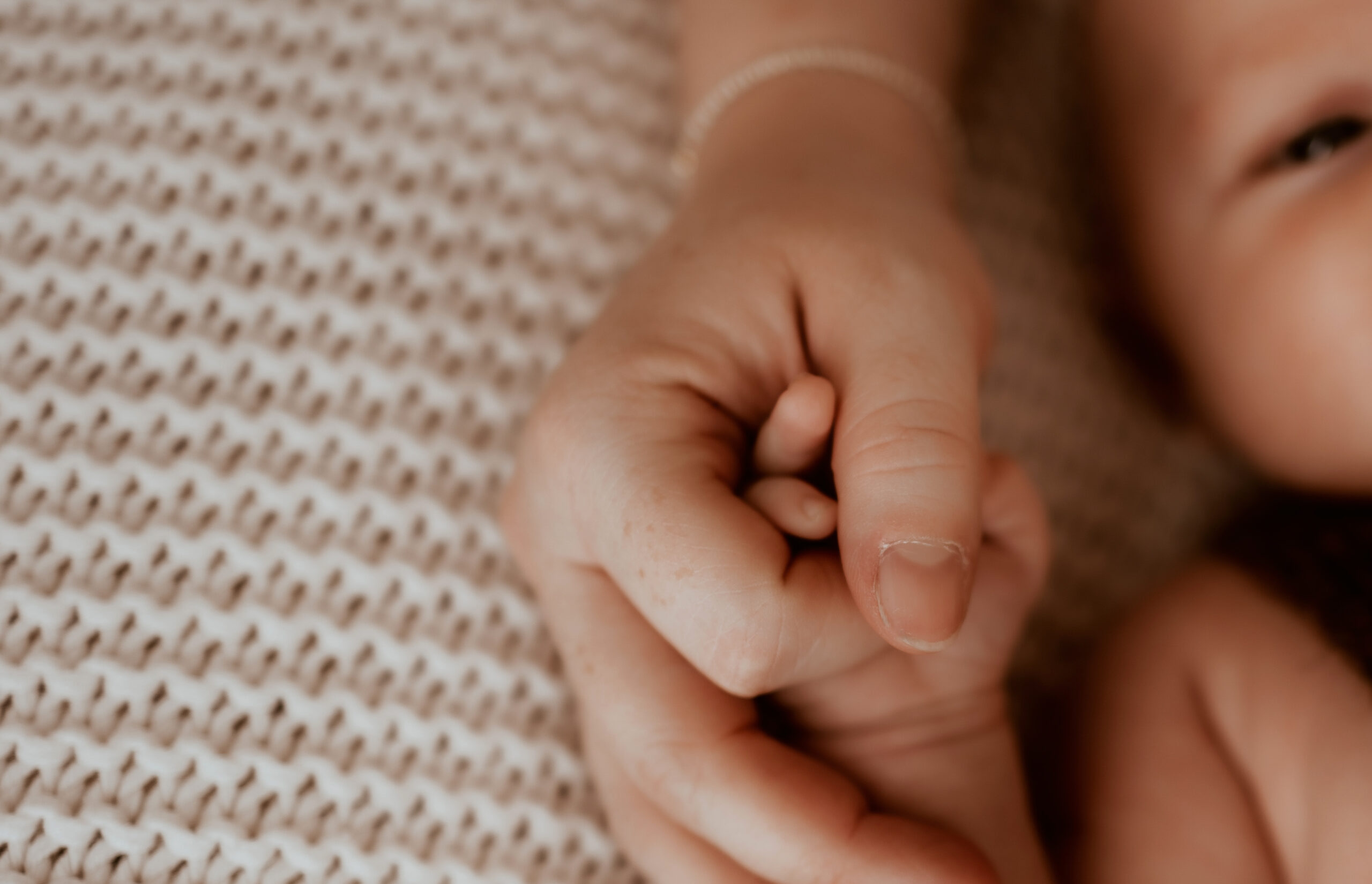 Newborn baby boy holding moms hands during indoor newborn session in Denver